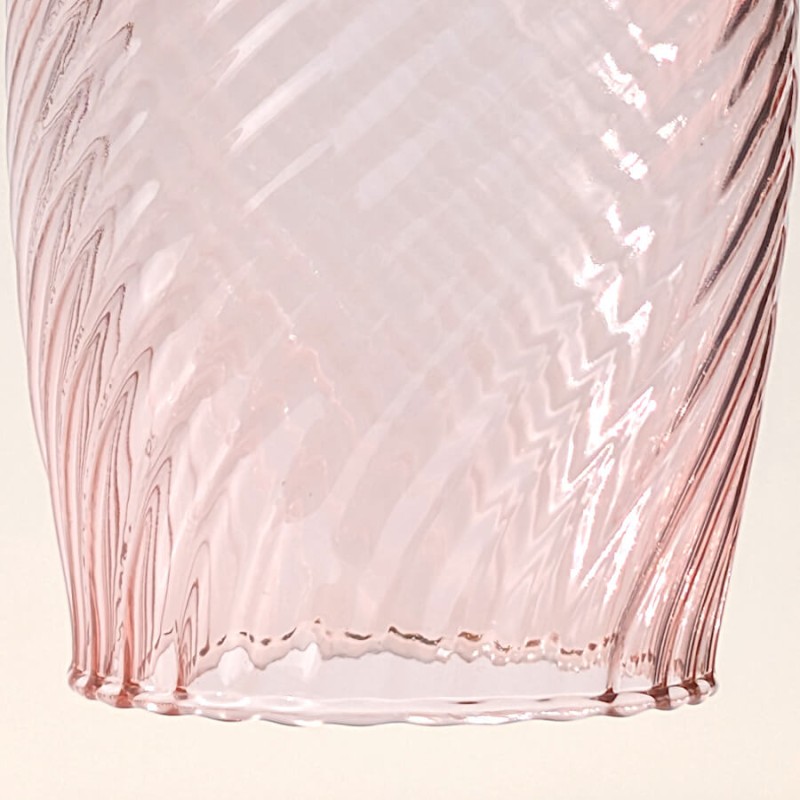 Focus macro sur le motif en chevrons gravé dans le verre rose.