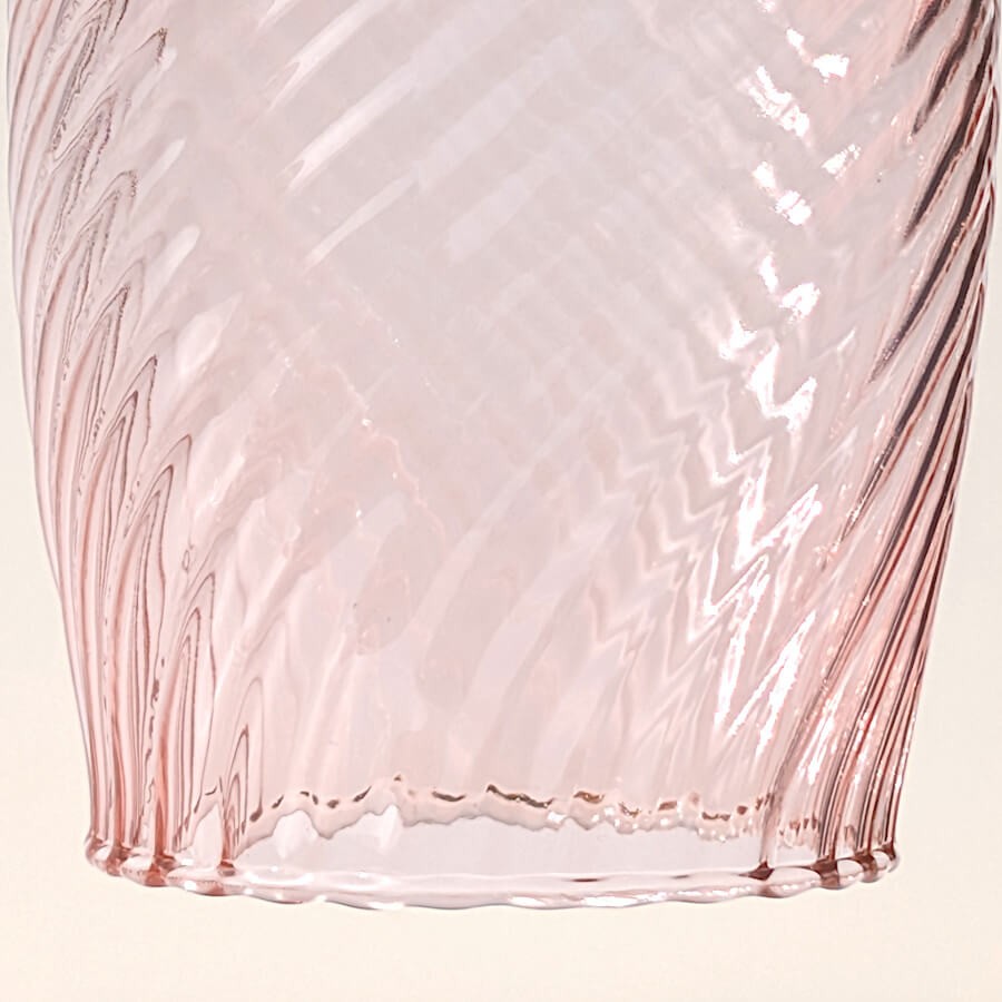 Focus macro sur le motif en chevrons gravé dans le verre rose.