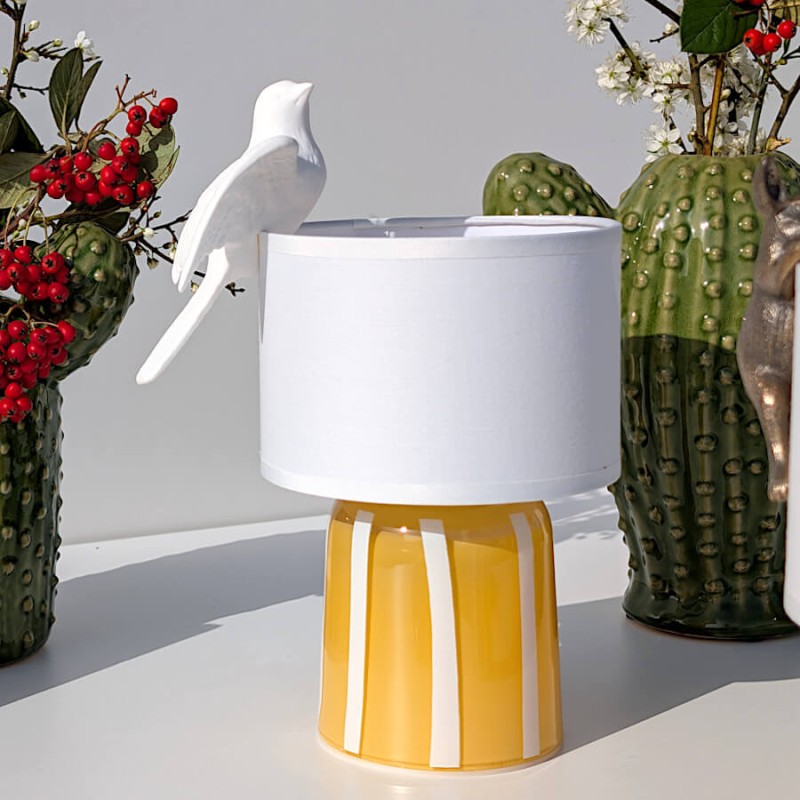 La figurine présentée dans un environnement lumineux avec des baies rouges, sur notre lampe à LED nomade en verre.