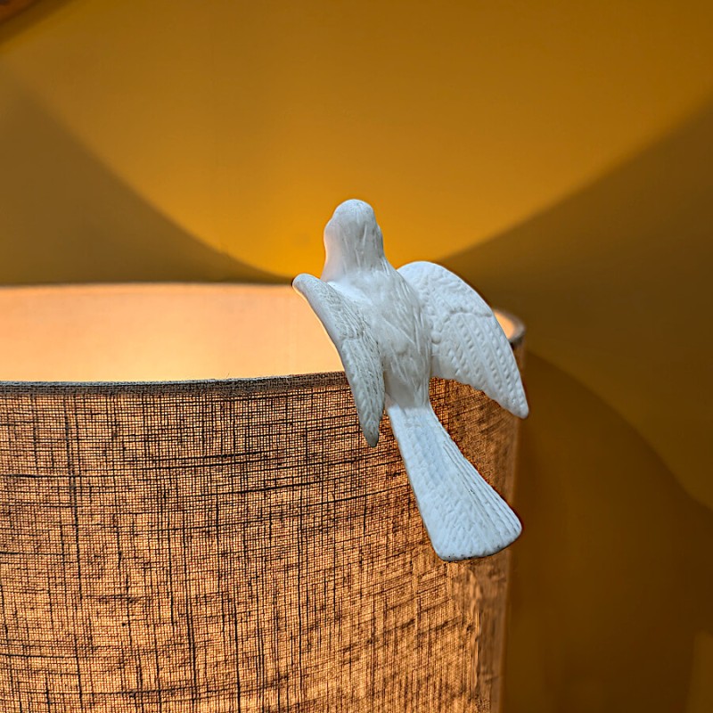 Contraste poétique de la céramique blanche sur un abat-jour en lin naturel.