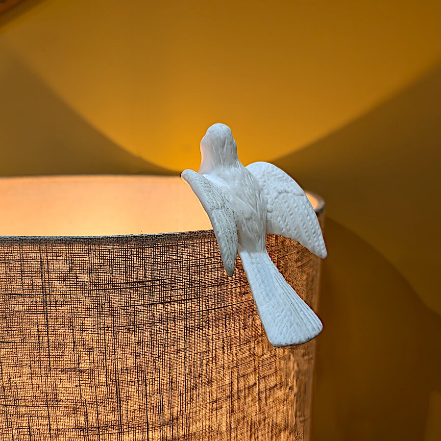 Contraste poétique de la céramique blanche sur un abat-jour en lin naturel.