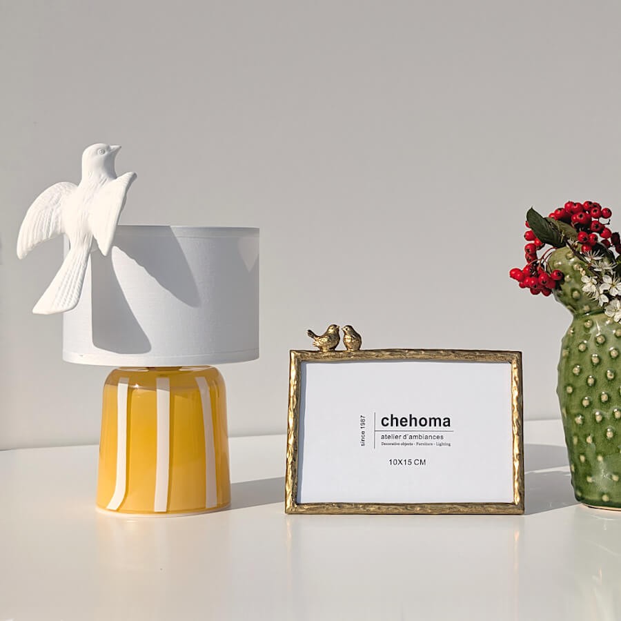 La colombe surplombant un décor composé d'un vase cactus et d'un cadre photo doré Deco-Delight.