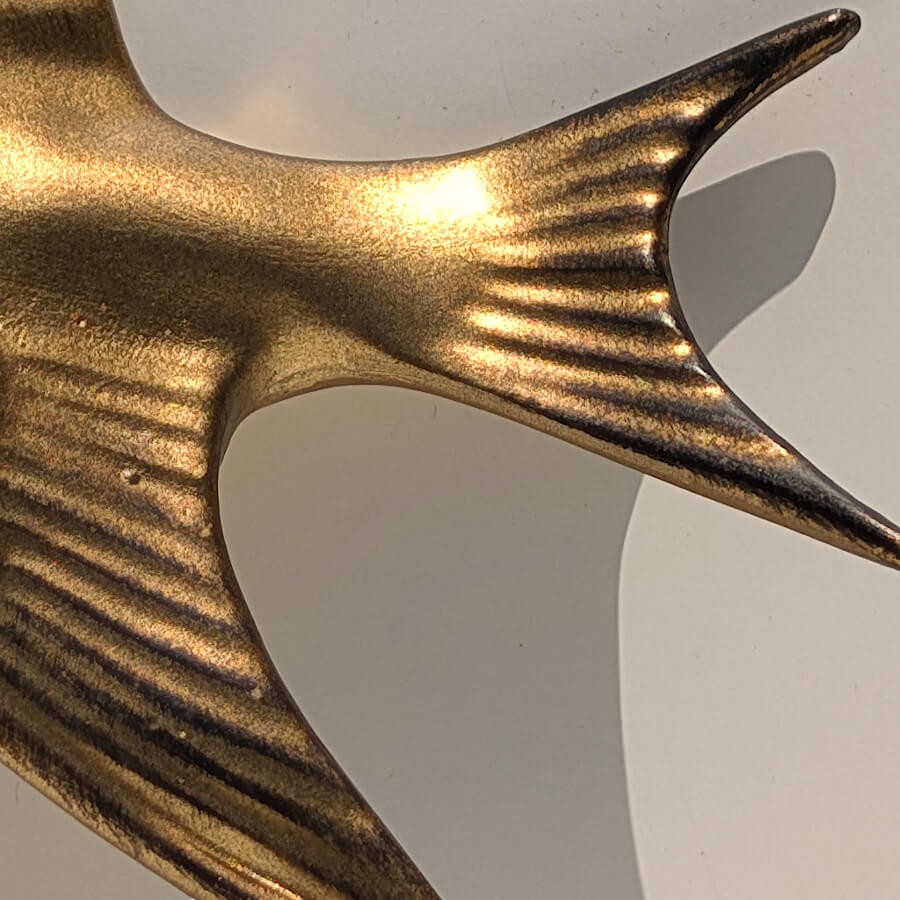 Zoom sur les plumes de la queue et la texture de la dorure.