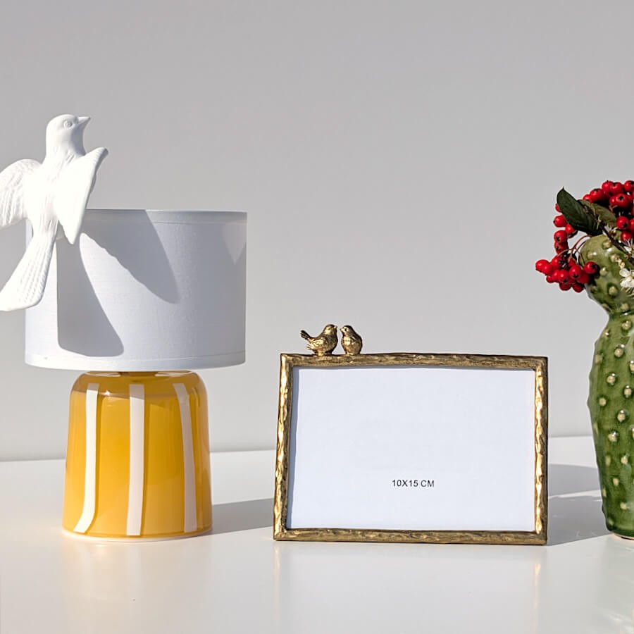 Le cadre photo oiseaux inséparables à côté de la lampe LED nomade en verre jaune de Deco-Delight.