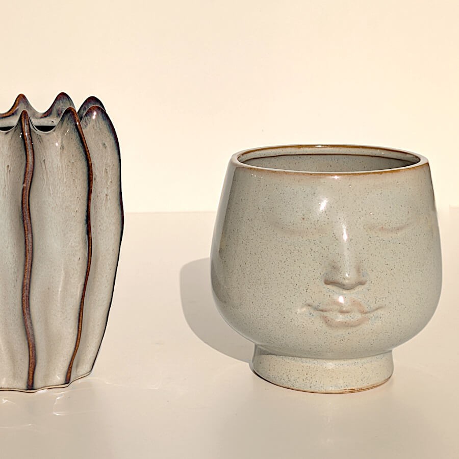 Présentation à côté d'un vase en céramique côtelé.