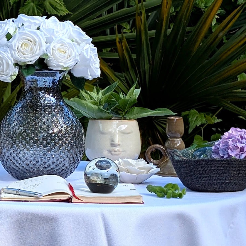 Le cache-pot visage trônant au centre d'une table fleurie.