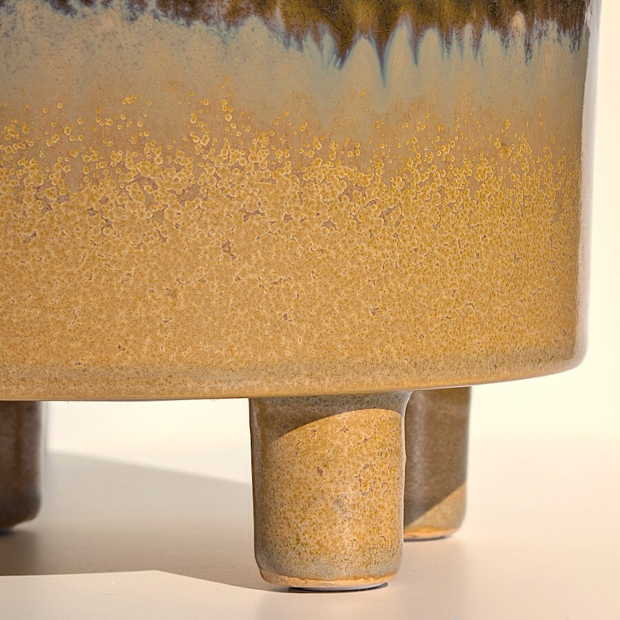 Gros plan sur la texture mouchetée et la base ocre du cache-pot.