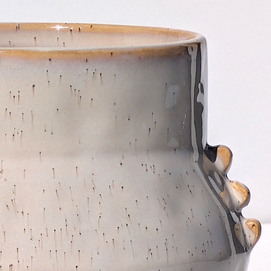 Zoom sur la texture de l'émail et les nuances de beige, avec les picots du pot.