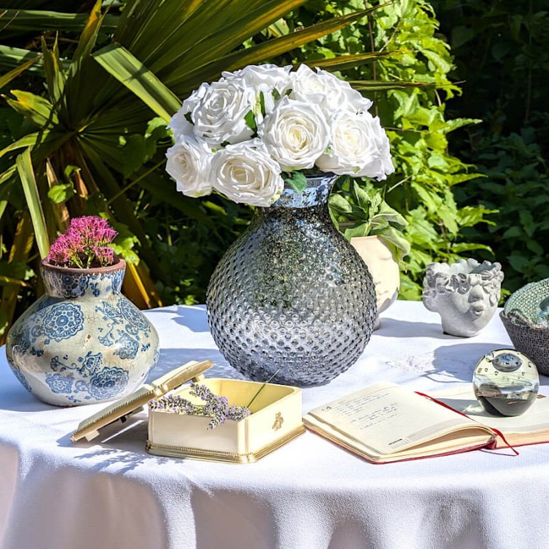 Scène déco complète sur nappe blanche avec vases et fleurs artificielles Deco-Delight.
