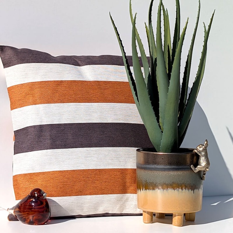 Ambiance cosy avec le coussin caramel rayé et accessoires terre cuite de la collection Deco-Delight.
