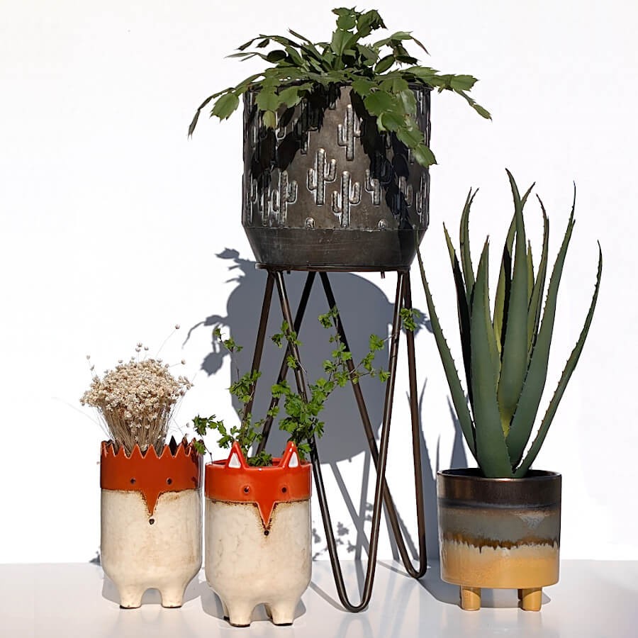 Composition de plantes vertes avec cache-pots texturés et renard et hérisson décoratif.