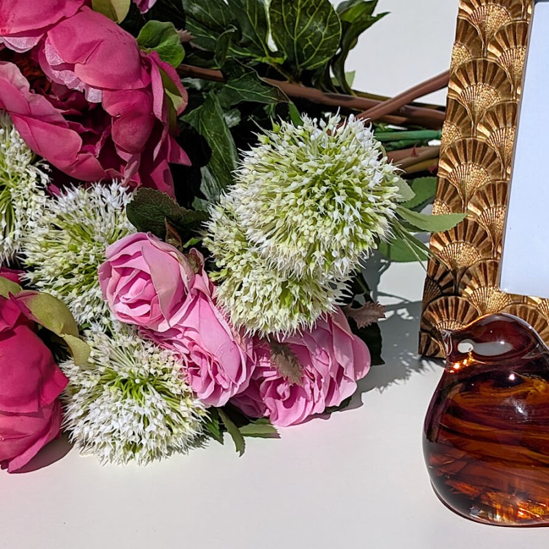 Focus sur l'association Allium et pivoines fuchsia avec le sulfure oiseau ambré en verre.