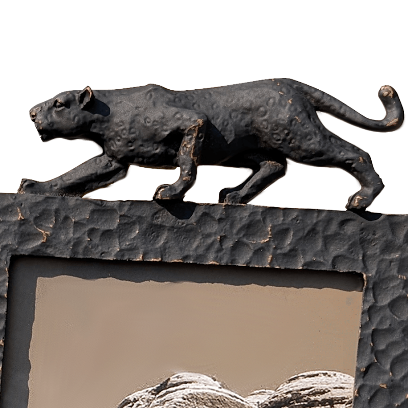 Gros plan sur la texture martelée du métal noir et les détails de la sculpture.