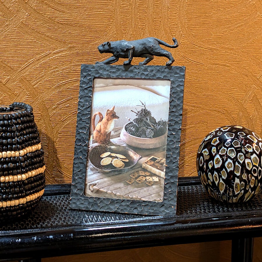 Le cadre exposé sur une surface texturée à côté d'un vase et d'une sphère décorative.