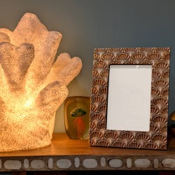 Présentation du cadre sur une console près d'une lampe corail.