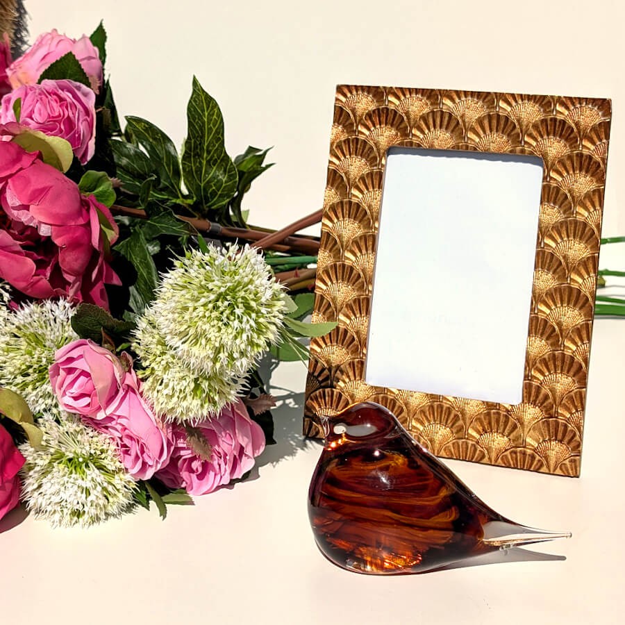 Ambiance déco avec fleurs, statuette oiseau et cadre assorti.