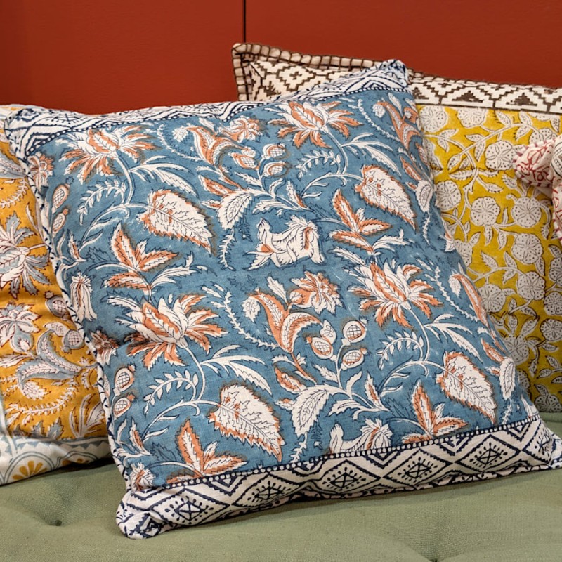 Association du coussin bleu avec un coussin jaune sur un canapé vert.