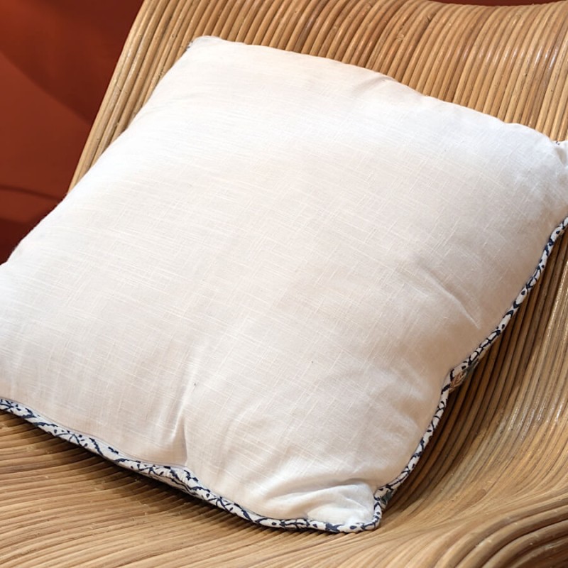 Vue du revers du coussin, montrant la face unie crème en coton.