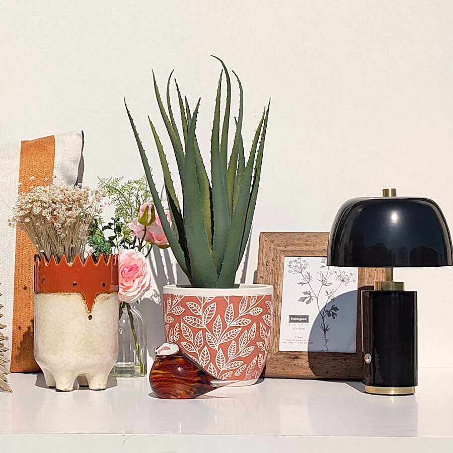 Ambiance bureau chic avec lampe noire, cadre noyer et touches végétales rafraîchissantes, collection Deco-Delight.