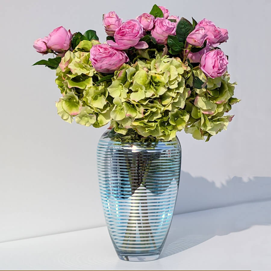 Bouquet d'hortensia vert et pivoines roses en vase bleu strié Deco-Delight pour un centre de table printanier.