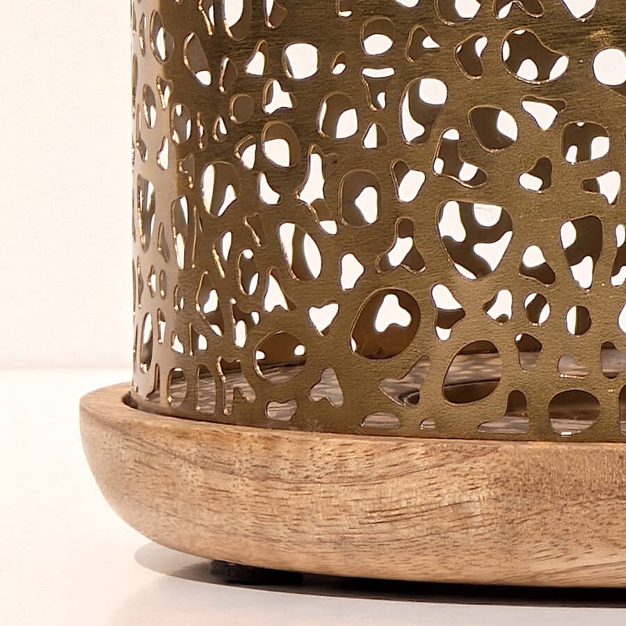 Zoom sur les motifs ajourés du métal doré créant des jeux d'ombres et de lumières uniques.