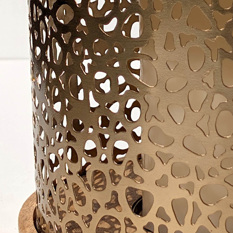 Zoom sur les motifs ajourés du métal doré, offrant une diffusion de lumière graphique et chaleureuse.