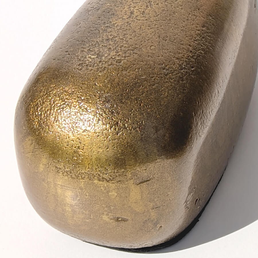 Zoom sur le corps de la baleine révélant la texture martelée du métal doré antique.