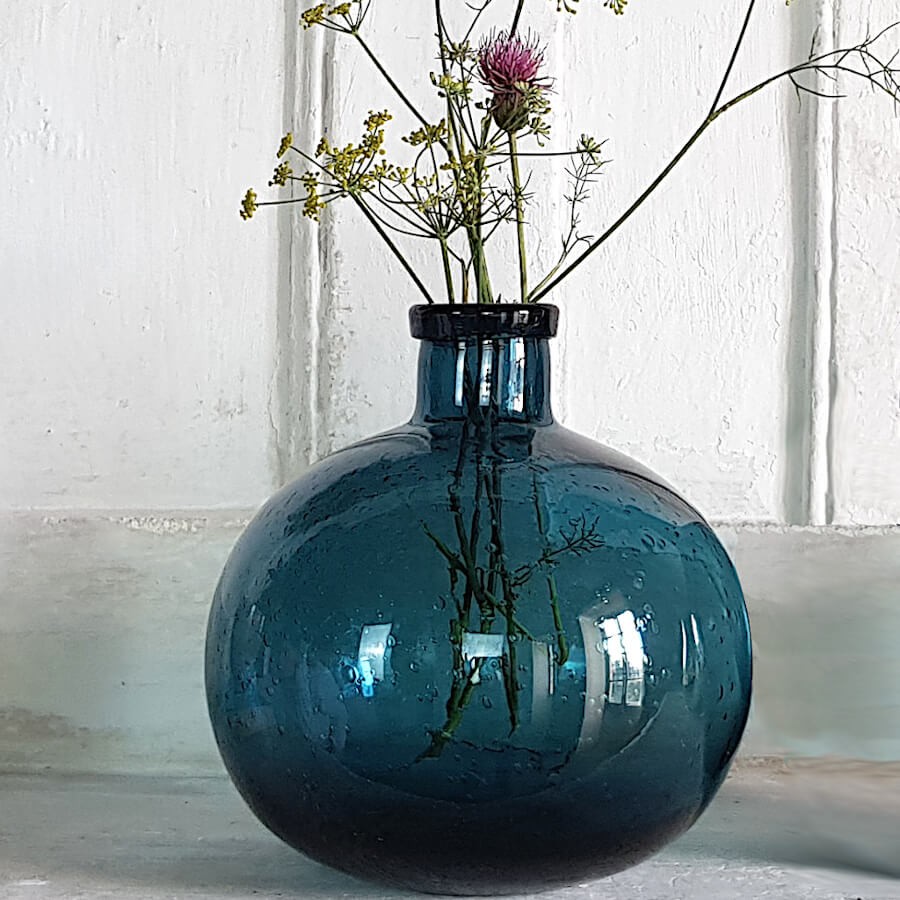 Vase boule bleu avec des fleurs séchées, en situation dans un intérieur au style authentique.