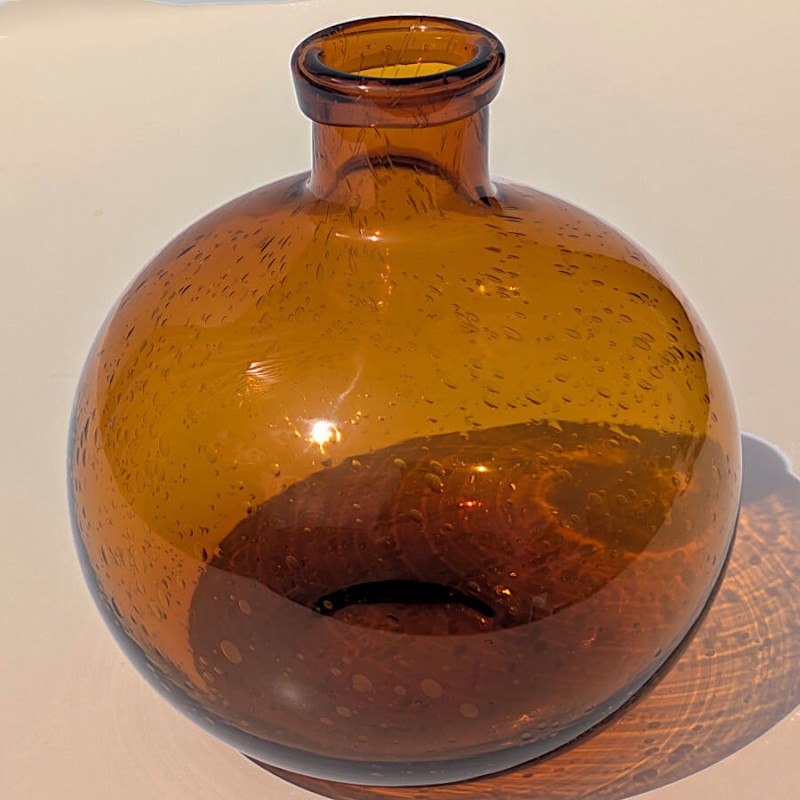 Jeu d'ombre et de lumière créé par le vase ambré, apportant une touche chaleureuse à votre déco.