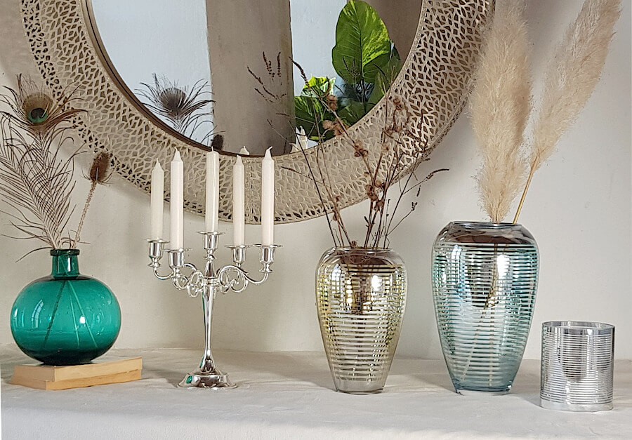 Mise en scène chic avec le vase en verre bullé, des vases lignés or et turquoise, un miroir, sur une cheminée.