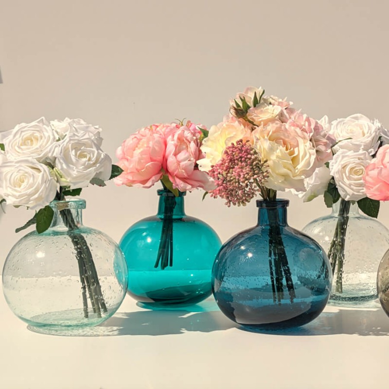 Le vase en verre bullé de couleur vert d'eau à côté de trois autres teintes de la collection Deco-Delight.
