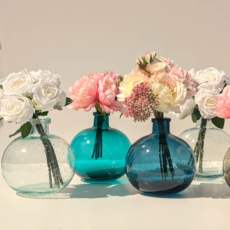 Le vase en verre bullé de couleur vert d'eau à côté de trois autres teintes de la collection Deco-Delight.