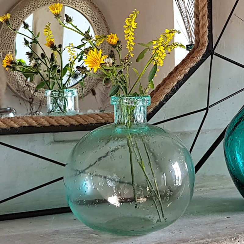 Des fleurs séchées dans le vase en verre bullé donnent un air champêtre, ici sur une cheminée devant un miroir.