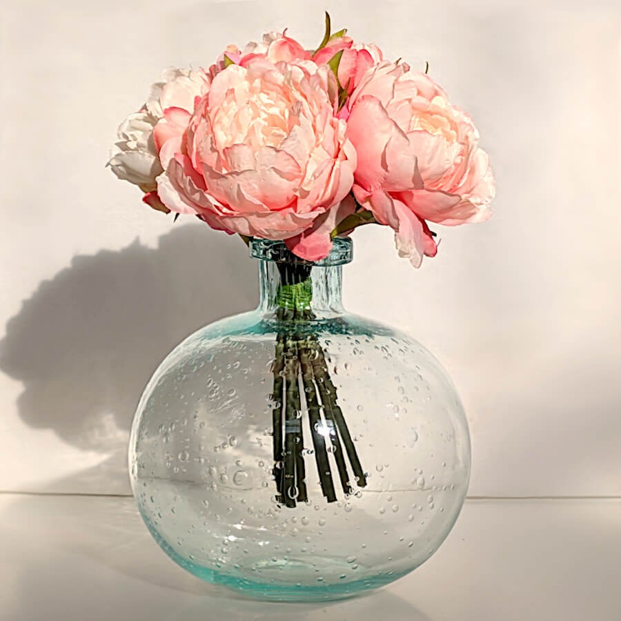 Un bouquet de roses ou de pivoines roses dans le vase en verre bullé vert d'eau crée immédiatement une atmosphère romantique.
