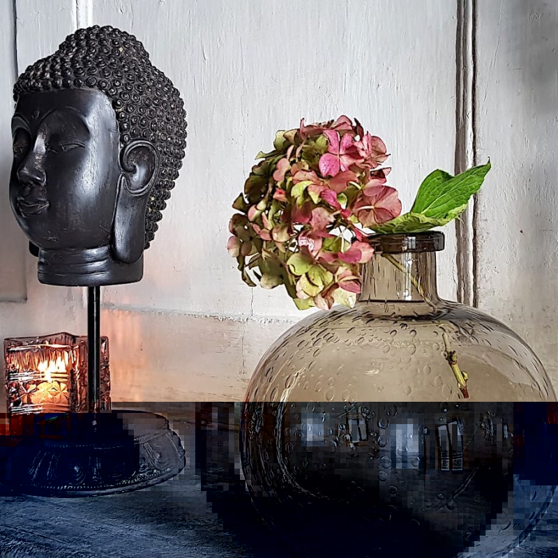 Mise en scène du vase en verre bullé marron dans une ambiance zen, avec une statue Tête de Bouddha (Deco-Delight).