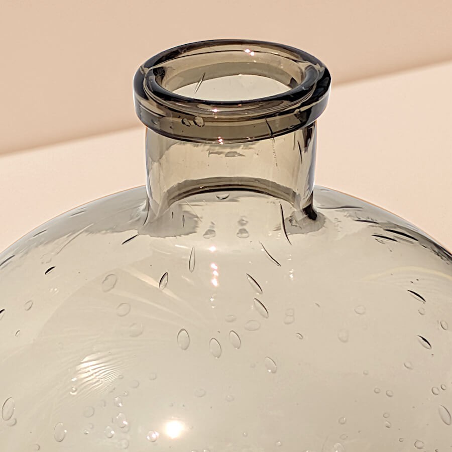 Zoom sur le col et la partie haute du vase en verre marron, montrant les bulles insérées dans le verre.