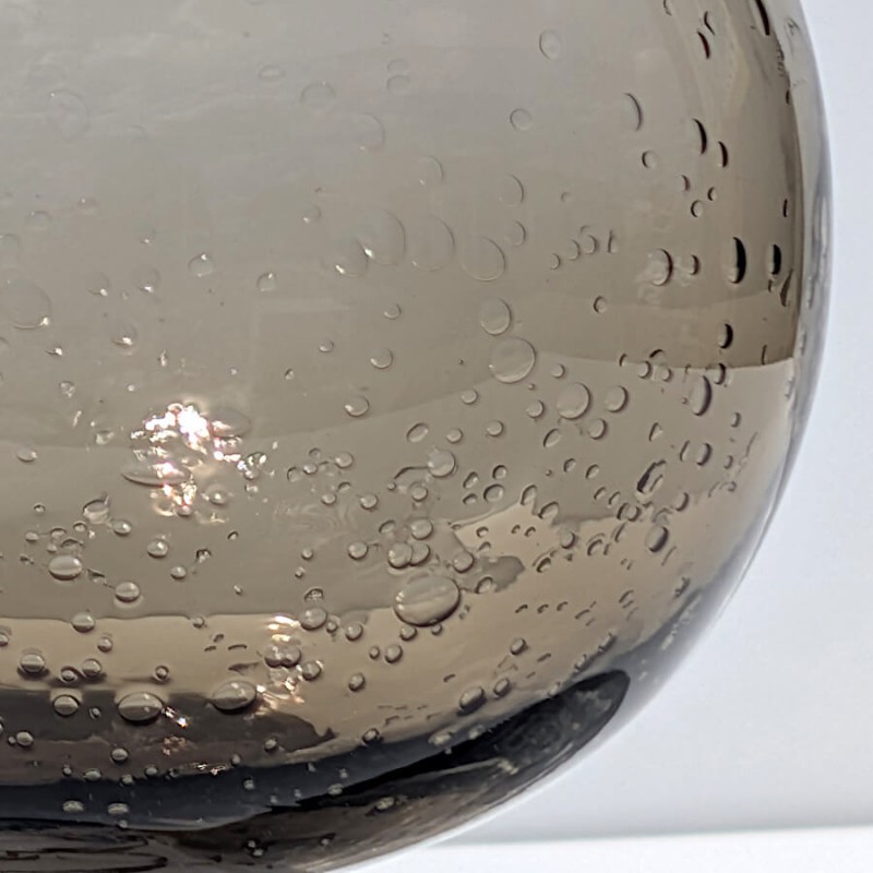 Détail de la forme arrondie du corps du vase boule en verre bullé de coloris marron.