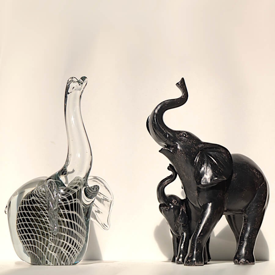 Duo de contrastes : l'éléphant en résine noire aux côtés de la figurine sulfure en verre texturé.