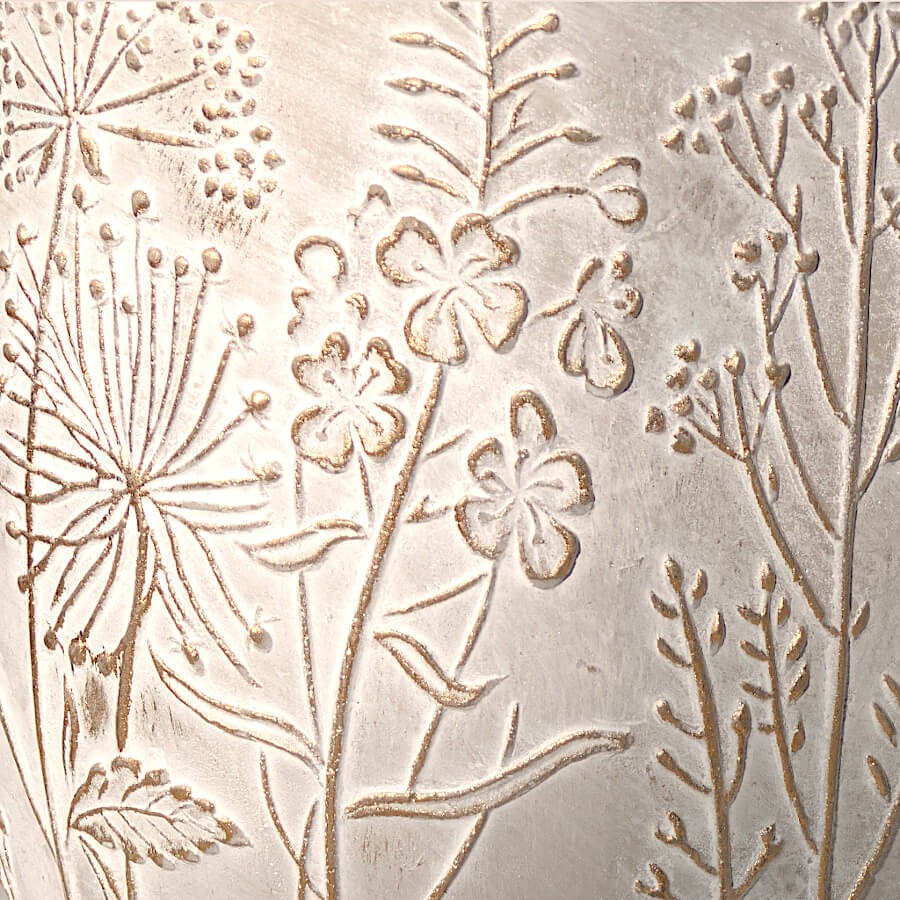 Détail de texture : Gros plan sur le relief des motifs floraux et le grain minéral du ciment.