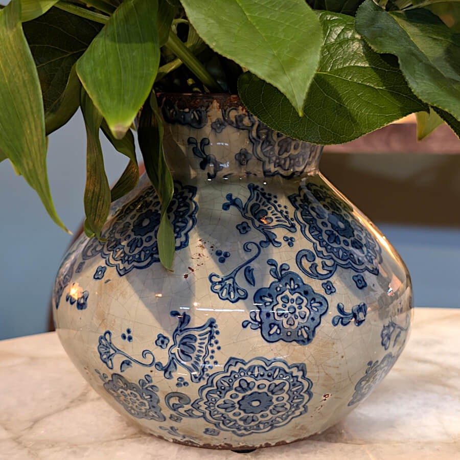 Le vase de 17 cm garni de feuilles de Pothos vertes, mettant en valeur le contraste entre le végétal et l'émail bleu.