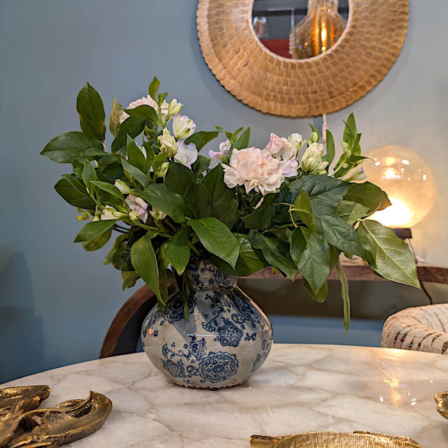 Le vase sur un plateau en marbre blanc au milieu d'un salon lumineux avec un bouquet de fleurs fraîches.