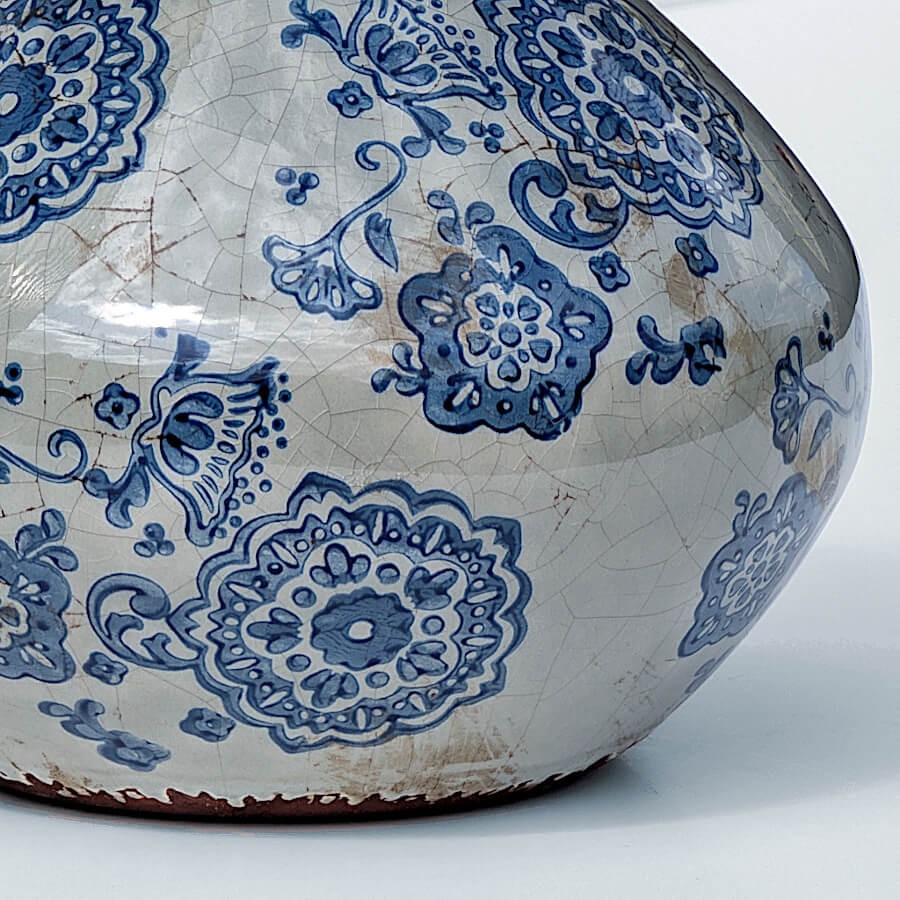 Gros plan sur le corps du vase montrant le réseau de craquelures délicates et la peinture florale bleue.