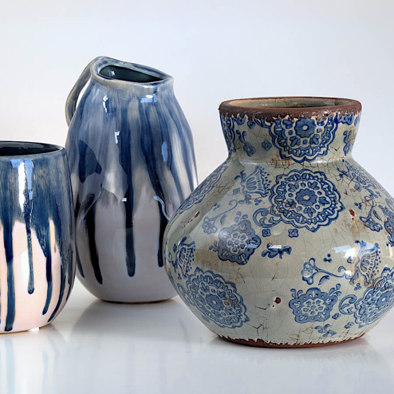 Duo de céramiques : Le vase floral présenté à côté de vases modernes aux coulures bleues abstraites.