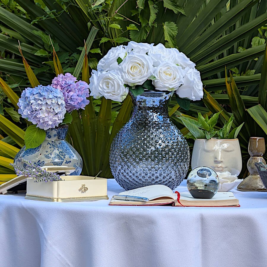 Le vase associé à un vase en verre gris texturé et à d'autres objets déco sous une lumière de fin de journée.