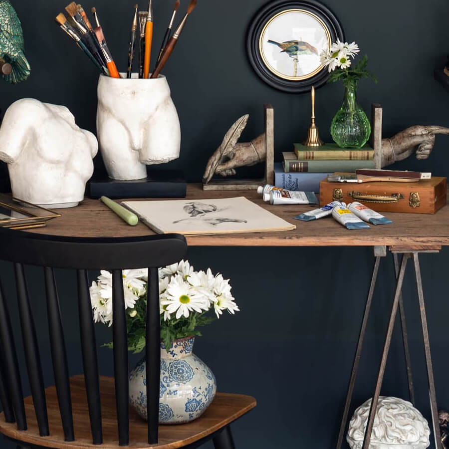 Décor atelier d'artiste : Le vase intégré dans un bureau créatif avec des pinceaux et une sculpture "buste" blanche.
