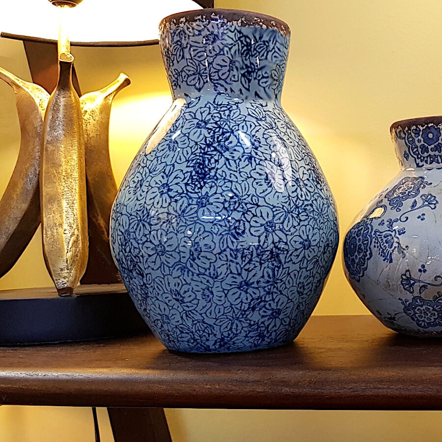 Ambiance tamisée : Le vase exposé sur une étagère en bois sous une lumière chaude, soulignant ses nuances de bleu.