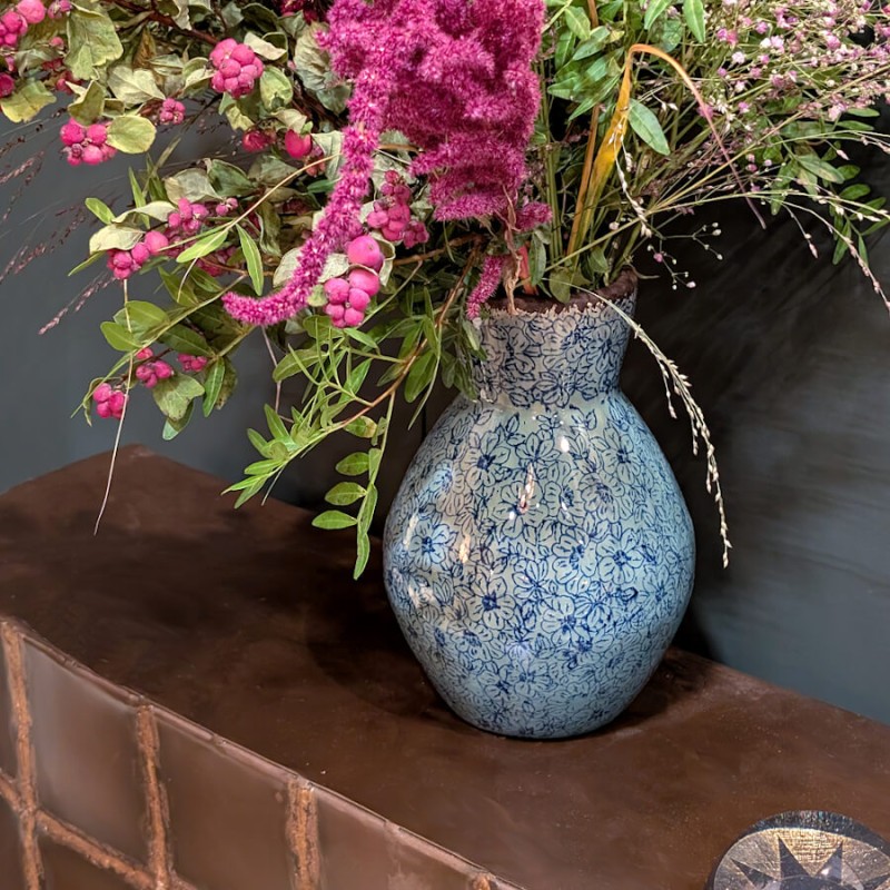 Composition florale haute : Le vase garni d'un bouquet de fleurs séchées et de graminées aux teintes pourpres.