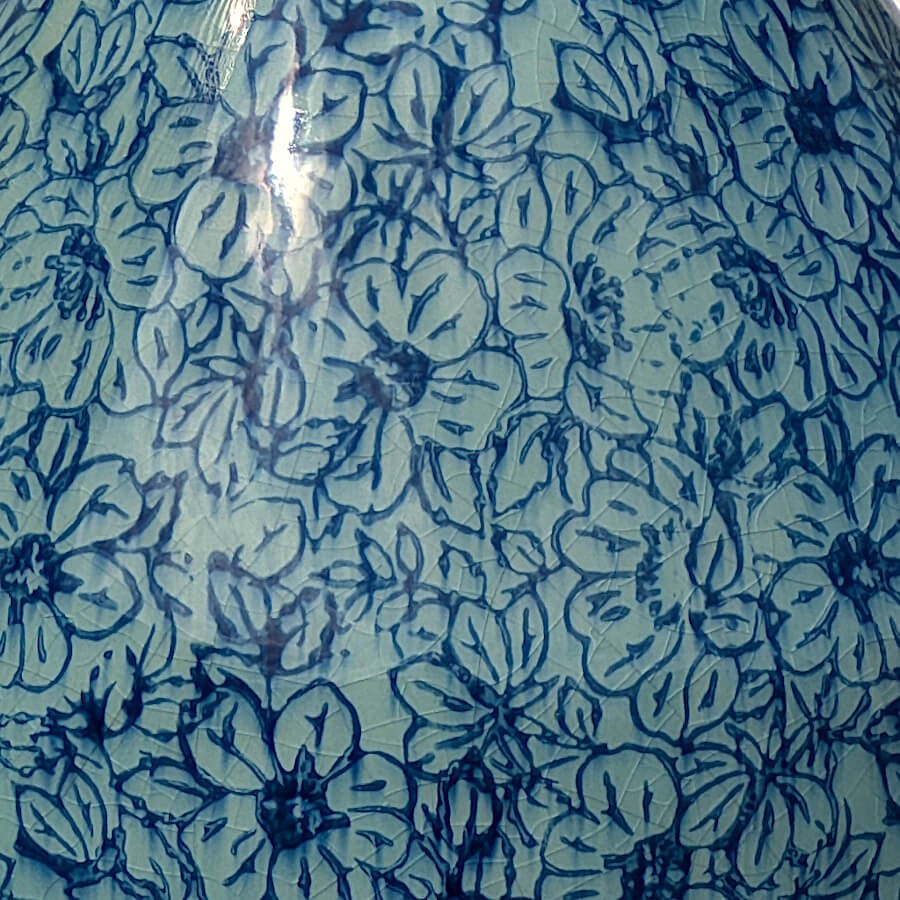Focus sur le motif : Gros plan sur les fleurs bleues stylisées qui recouvrent toute la surface du vase.