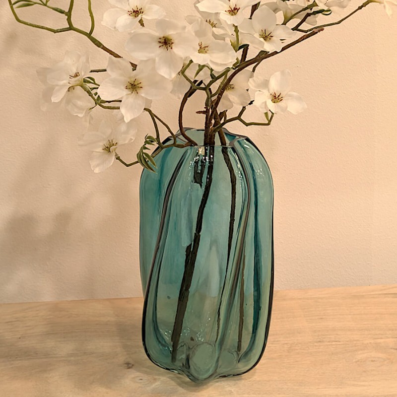 Mise en scène salon : Le vase garni de fleurs blanches sur une table basse, à côté de la lampe champignon Misty bleue.