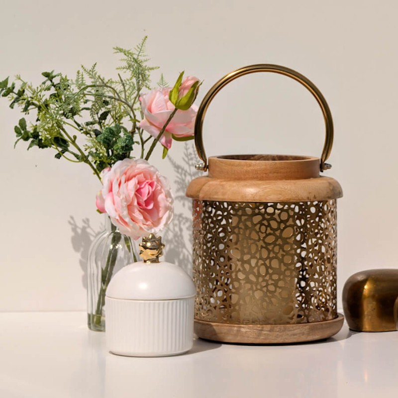 Ambiance chaleureuse : La composition florale près d'une lanterne dorée et d'une boîte en porcelaine blanche Deco-Delight.
